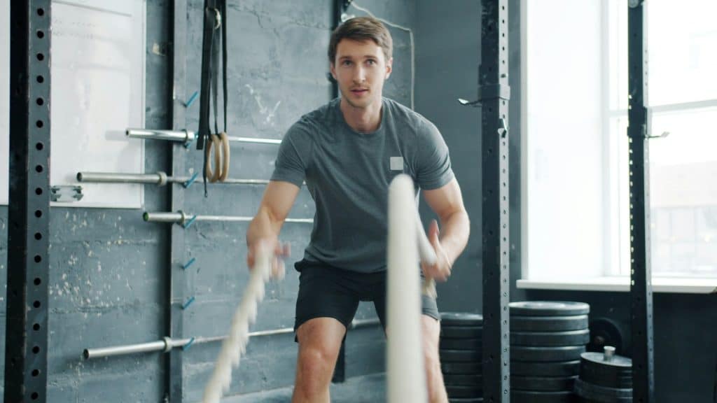 Man using ropes to work out in a gym.