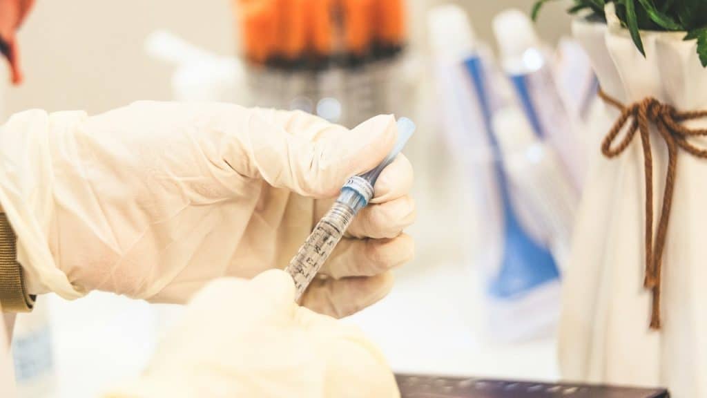 A close-up of a healthcare worker's gloved hands carefully preparing a syringe