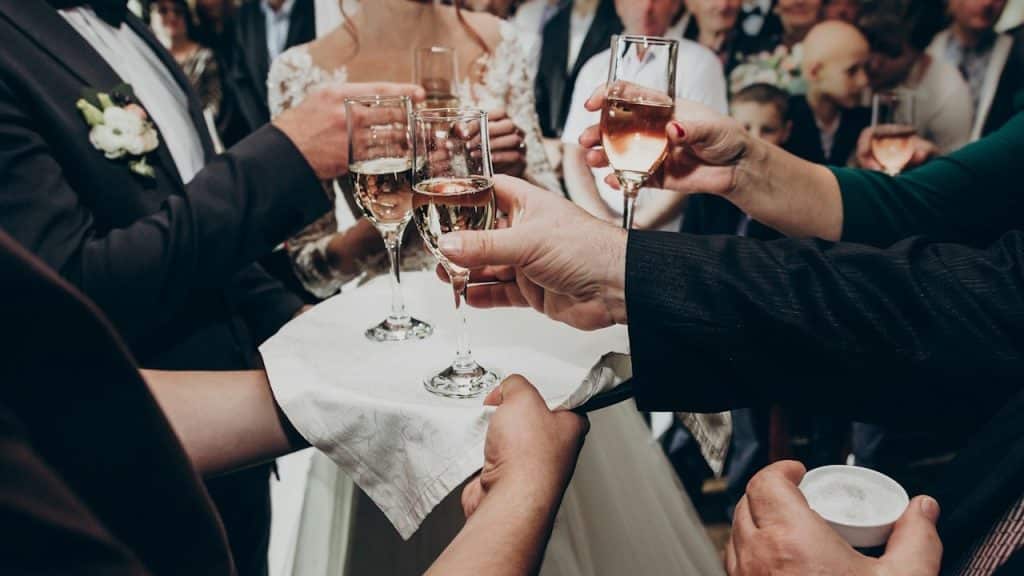 A close-up of people taking champagne glasses from a tray held by a server.