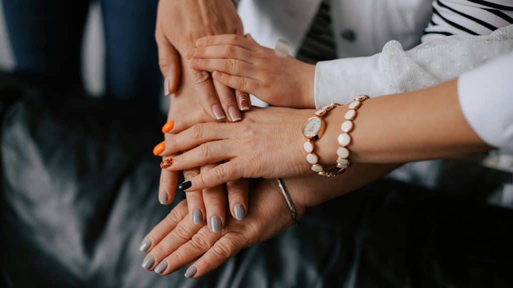 A close-up shot of several women from different generations stacking their hands on top of each other