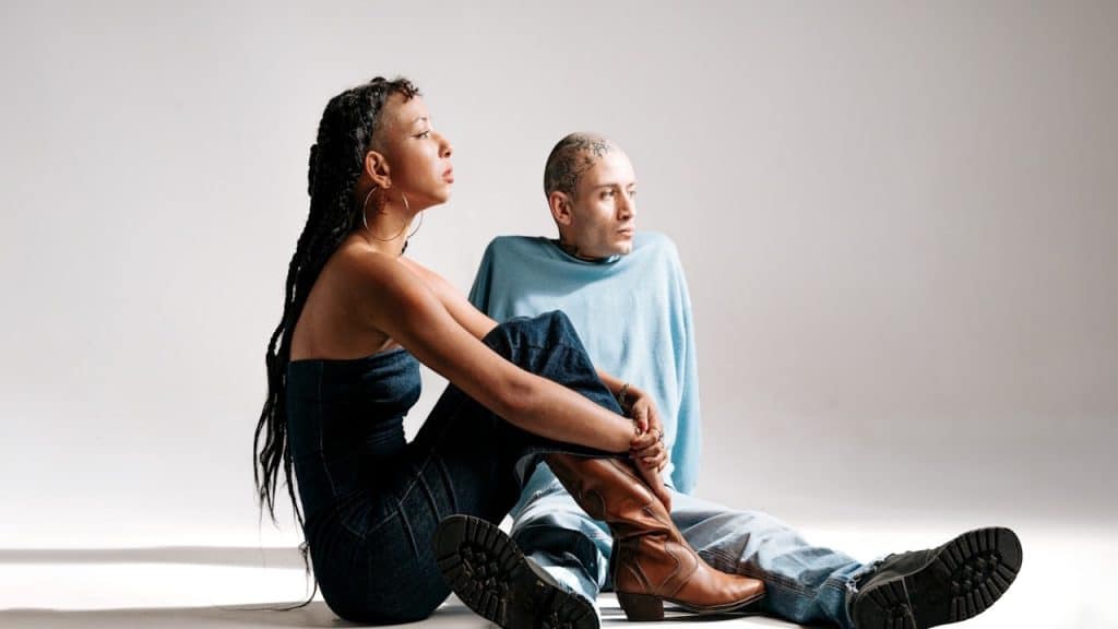 A women is sitting with hands on the covering knee and a men sitting with him bypassing the leg under women knees