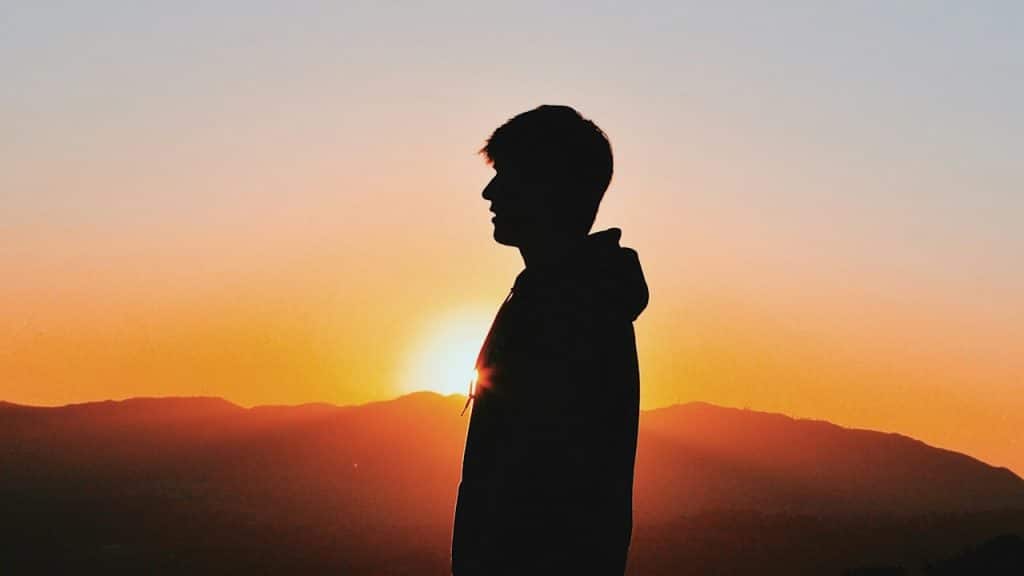 A man’s silhouette as he looks in the distance during sunset.