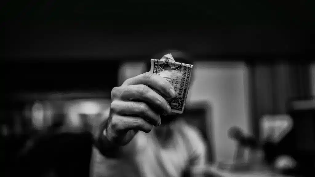 A man holding up a dollar note.