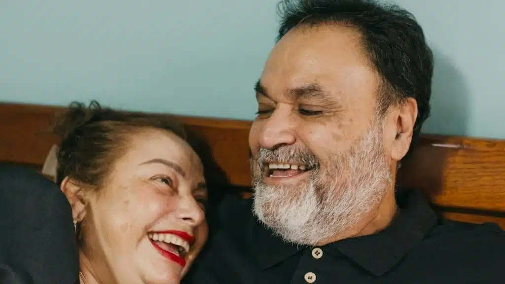 A man and a woman lying and laughing on a bed.