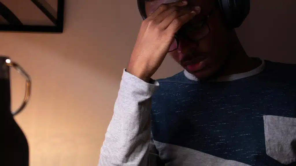 A person wearing headphones, holding their head in a stressed or tired moment.