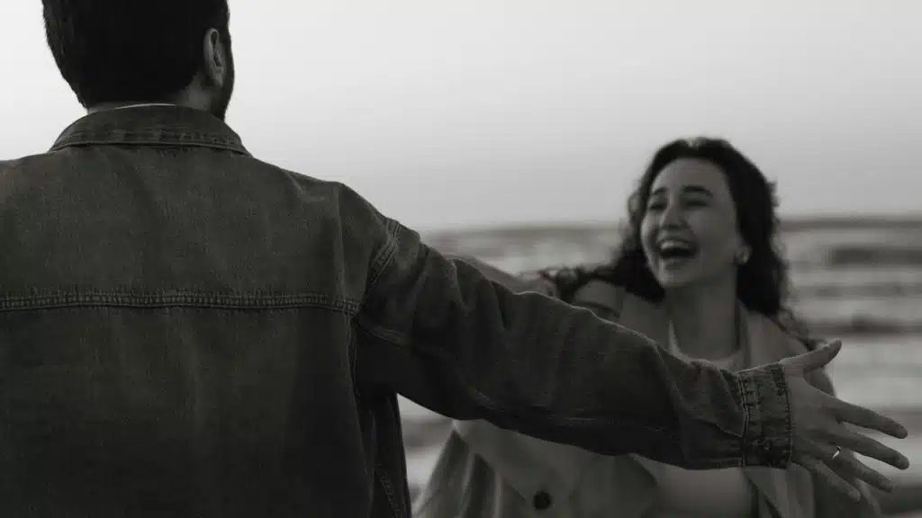 A man with open hands standing in front of a laughing woman who is coming towards him
