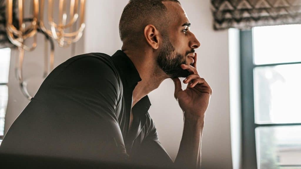 A man with his hand on his chin and a thoughtful expression on his face.