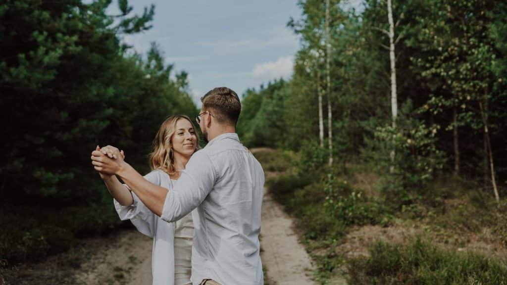 A pair of people dancing on a forest trail.