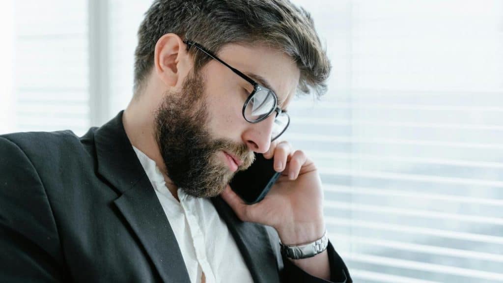 A man with a phone in his hand and a suit on his body.
