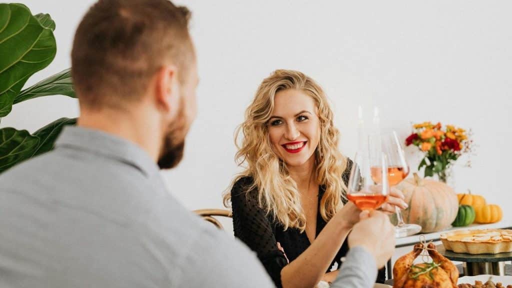 A man and a woman toasting with wine at a holiday dinner.