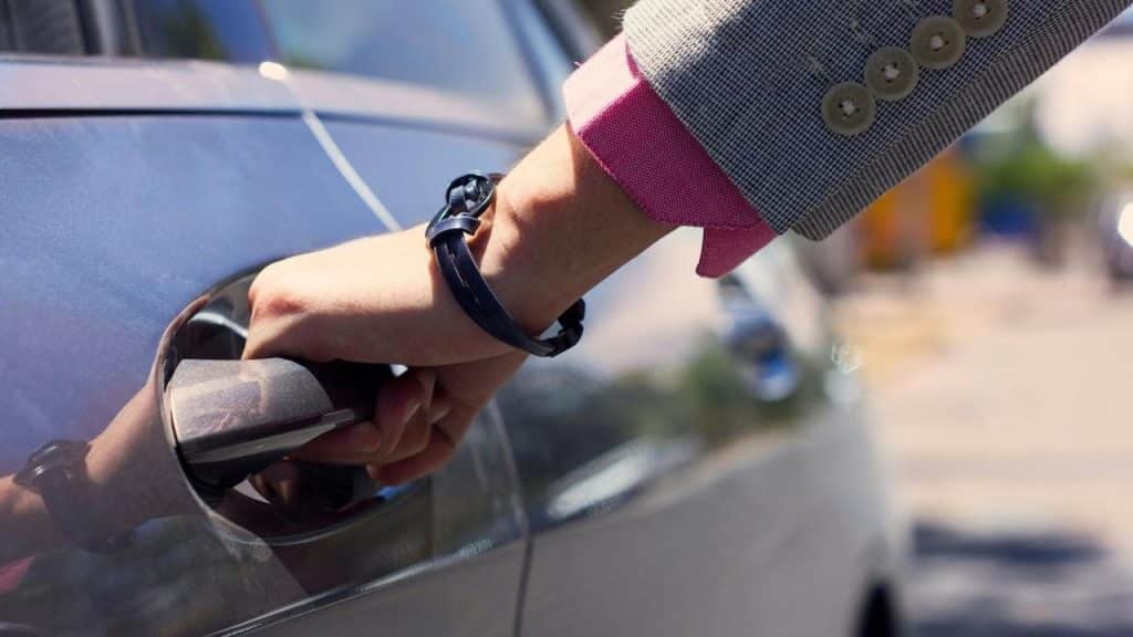 An individual pushing on a car door.