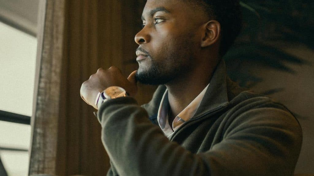 A man resting his chin on his hand and looking thoughtfully out a window.