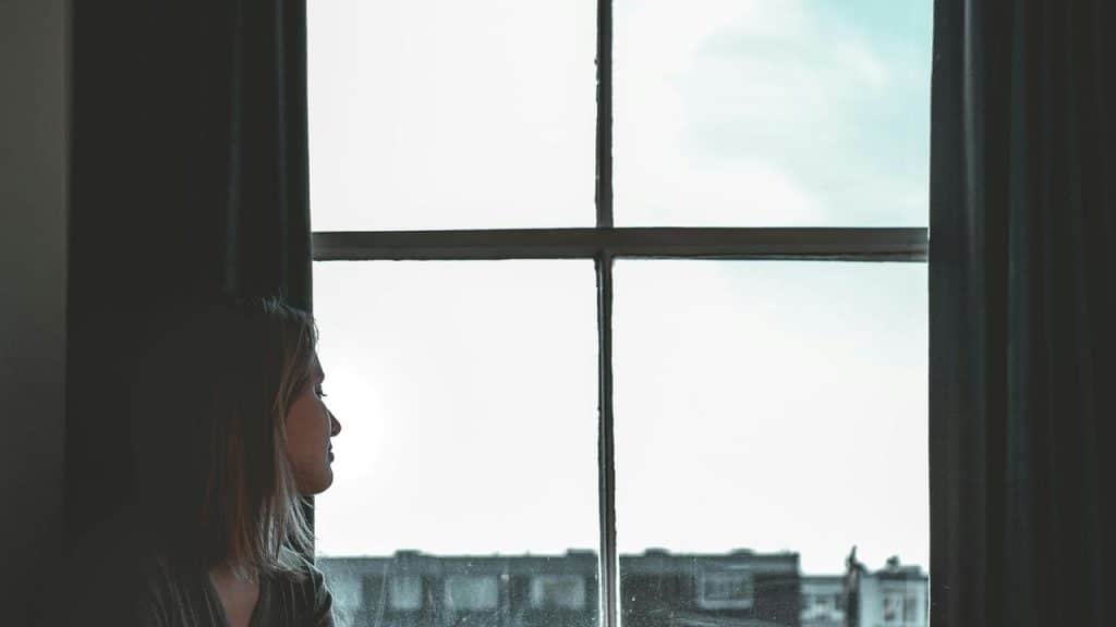 A woman in profile gazing out a large window
