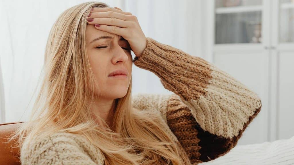 A woman holding her forehead with eyes closed, appearing to have a headache.