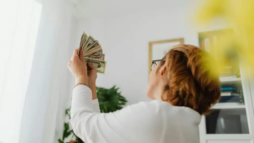 A person holding up a fan of cash and looking at it.