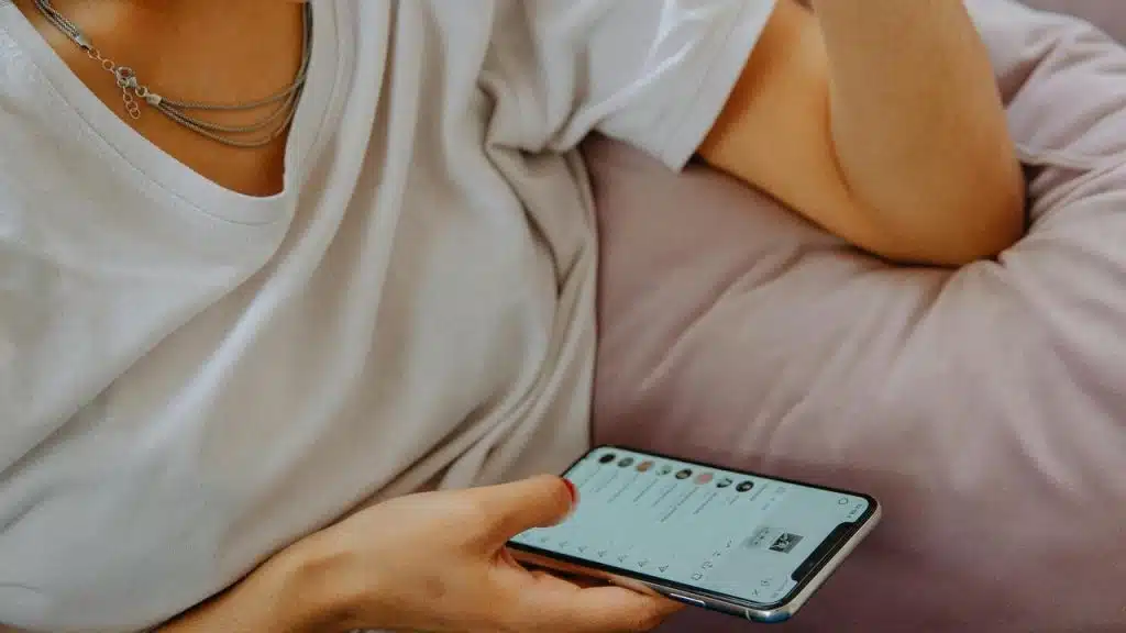 A person holding a smartphone while sitting on a couch.