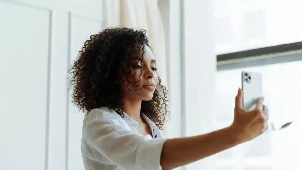 A woman taking a selfie with a smartphone indoors.