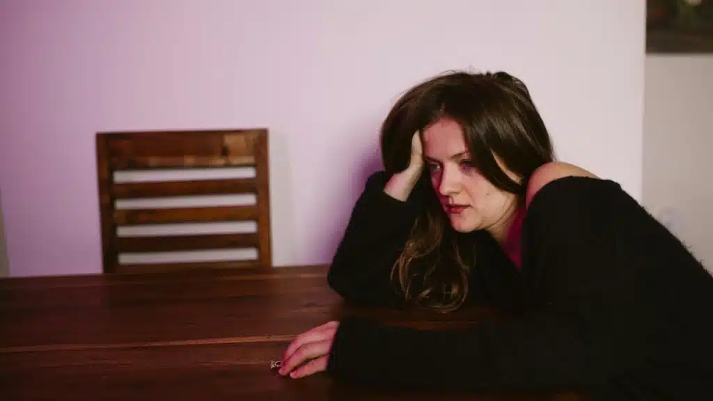 A woman resting her head on her hand while sitting at a table, looking tired.