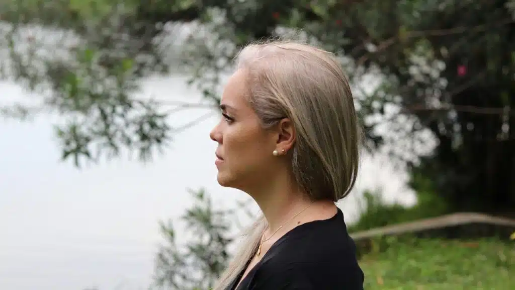 A woman with gray hair looking to the side outdoors.