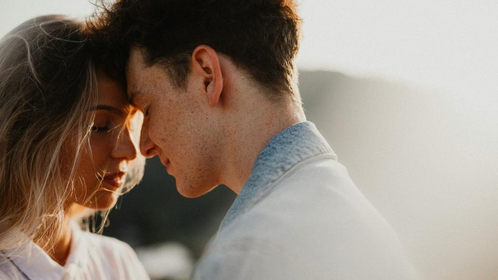 A couple touching foreheads in a tender moment outdoors.