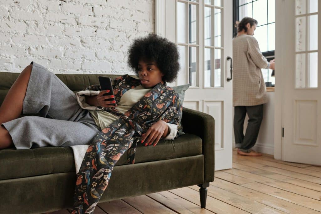 Woman relaxing on couch, man busy doing something