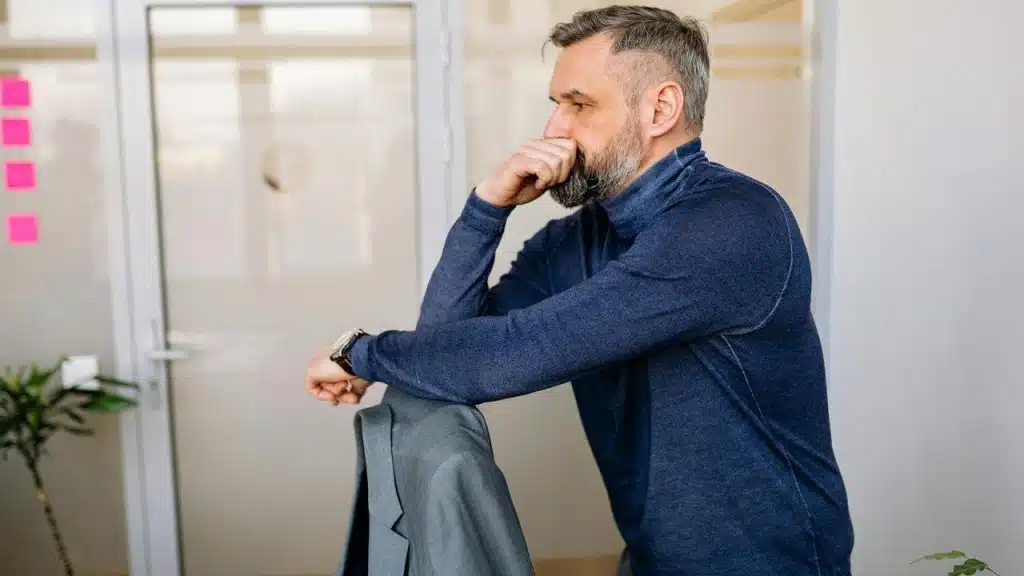 A man leaning on a chair, looking thoughtful in an office.
