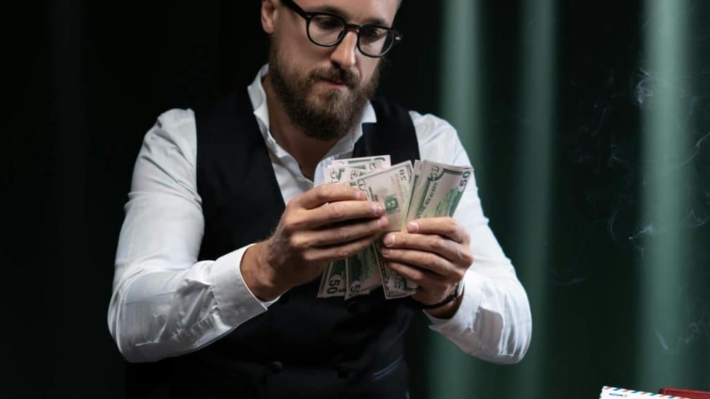 A man counting a stack of dollar bills while looking down.