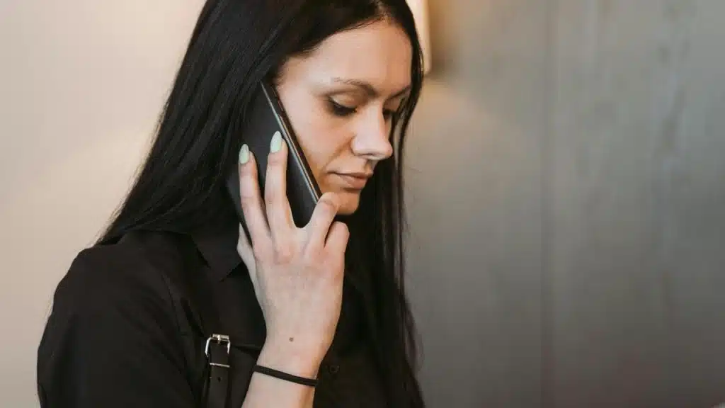 A woman holding a phone to her ear while looking downward.