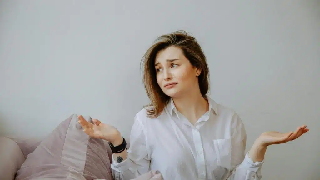 A confused woman shrugging with her hands raised.