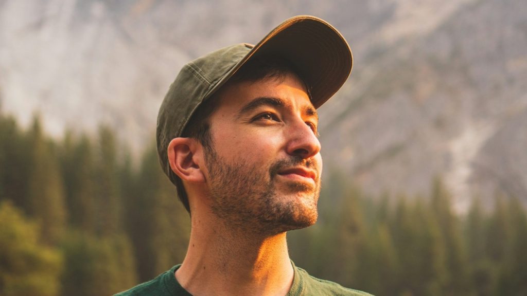 A thoughtful man standing in nature at daytime.