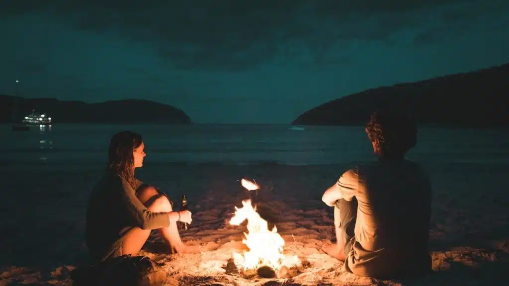 Man and woman with bonfire sitting on the seashore.