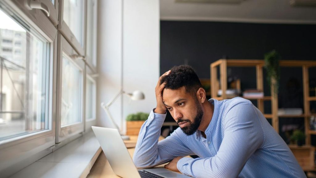 A man looking stressed at his laptop.