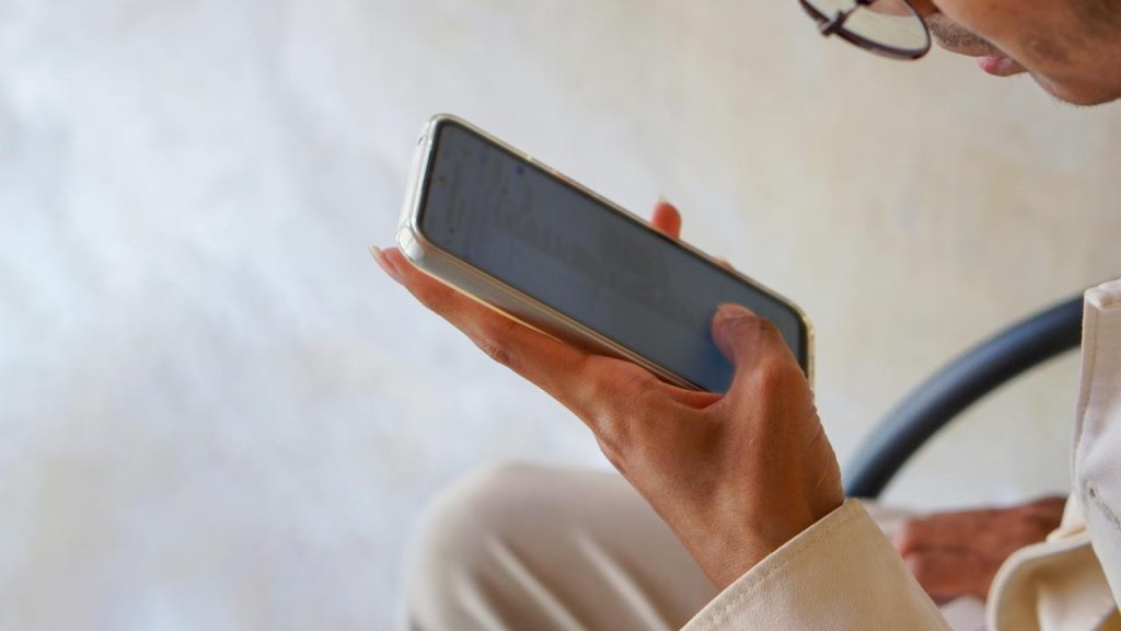 A person holding a smartphone and looking at the screen.