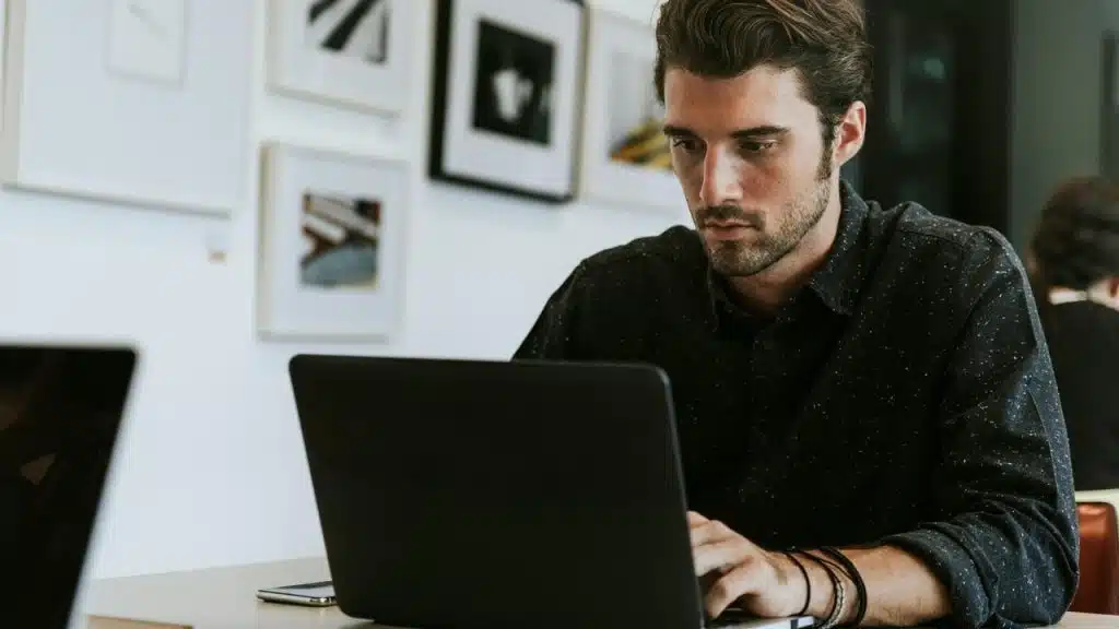 A focused man working on a laptop at a desk in a modern office.