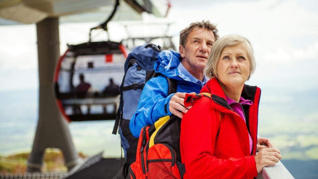 The senior-hikers couple is waiting for the cableway in the cable station.