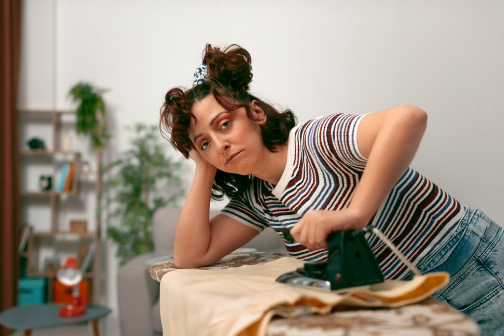 Tired Woman doing chores at home alone ironing clothes