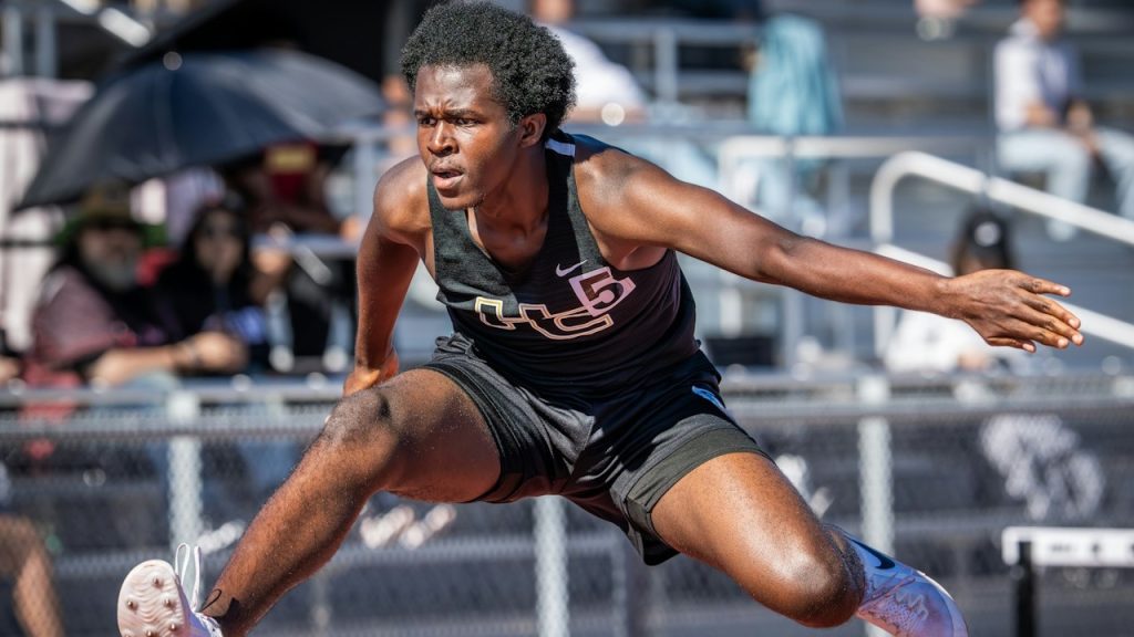 A male athlete hurdles during a track-and-field race.