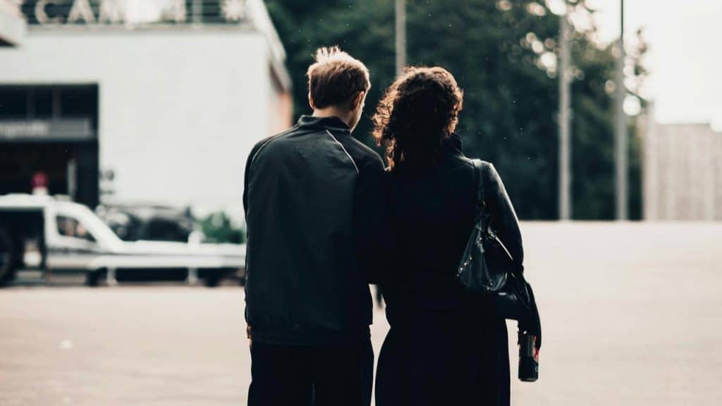 A couple walking side by side across an open urban space.