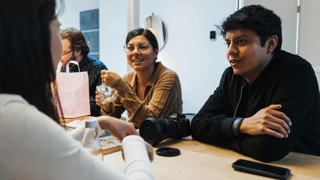 A group of people sitting at a table, chatting together.