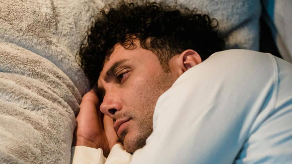 A man lying on his side, looking tired and pensive.