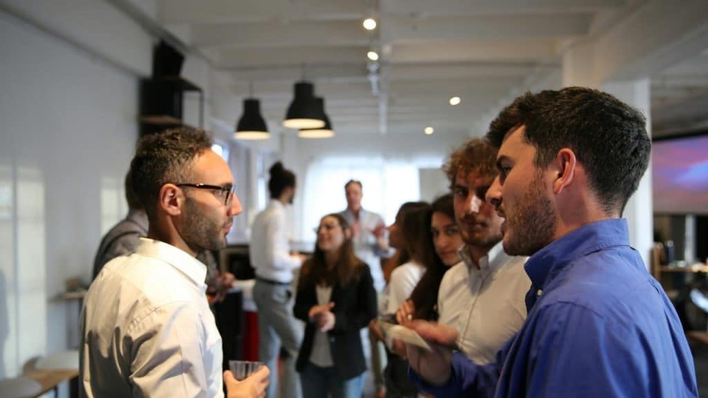 A group of people talking and networking in a bright office space.