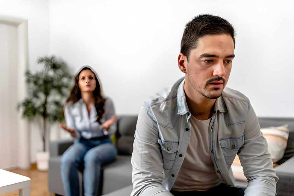 Distressed man ignoring his girlfriend behind him