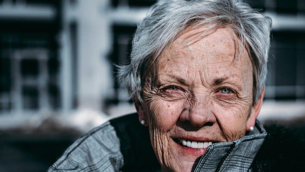An elderly woman smiling at the camera.