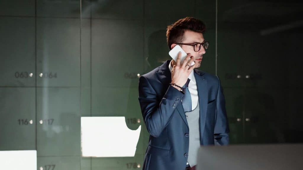 A man in a suit talking on a smartphone in a modern office.