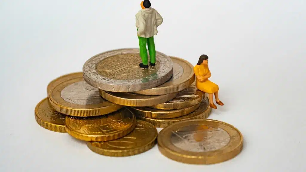 A man standing on the stack of gold and lady sitting beneath it