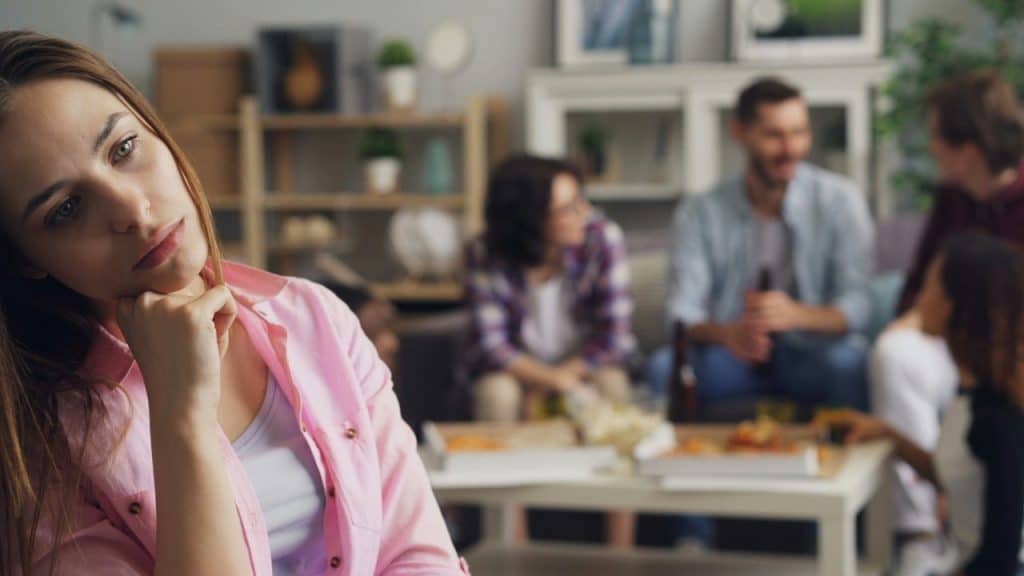 A woman in a pink shirt looking forward while a group of people talk behind her.