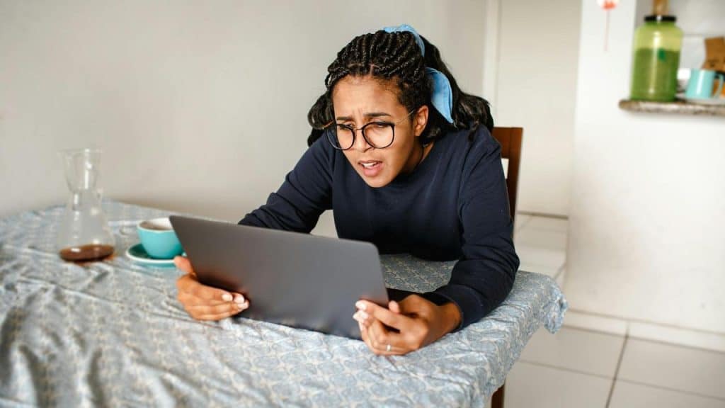 A person looking frustrated while using a tablet at a table.
