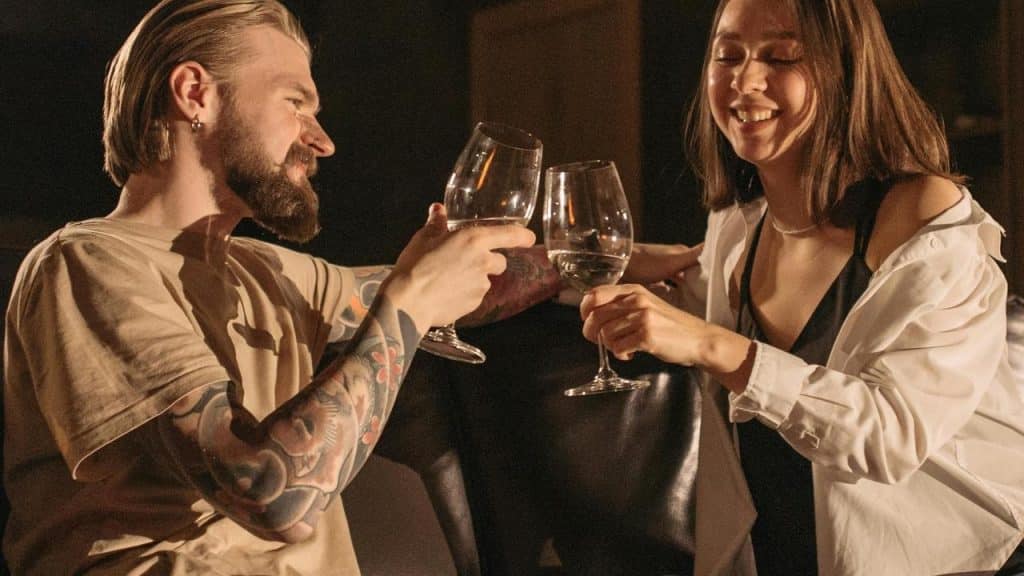 A smiling couple clinking wine glasses in a warmly lit setting