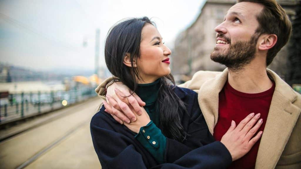A couple embracing and smiling while standing on a city street