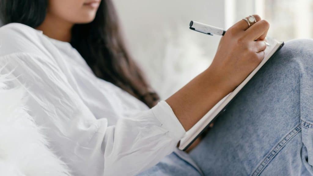 A person writing in a notebook while sitting comfortably indoors.